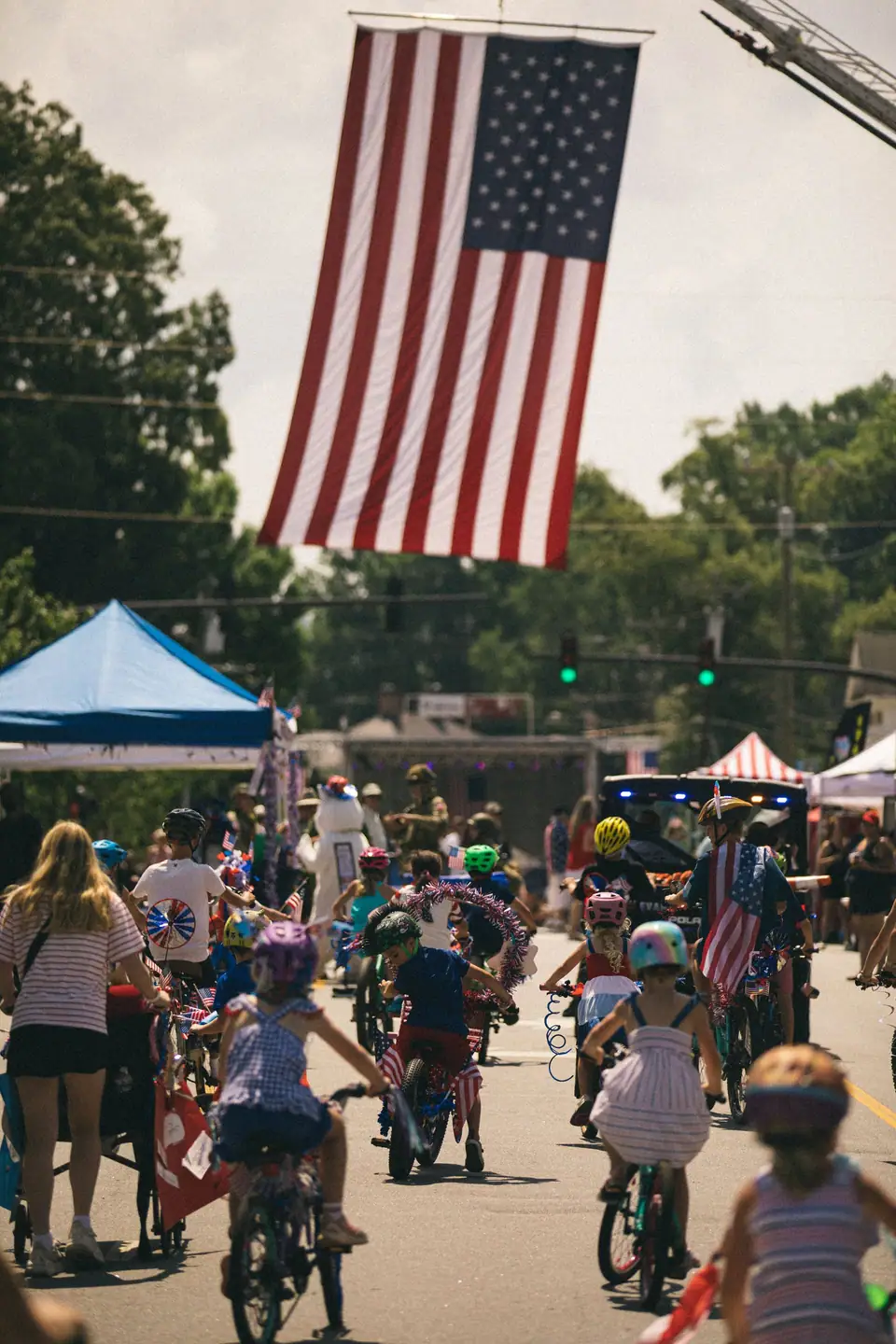 Children seen from behind riding decorated bikes in a Fourth of July parade