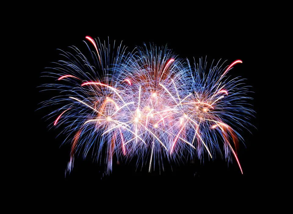 Red, white and blue fireworks bursting against a night sky
