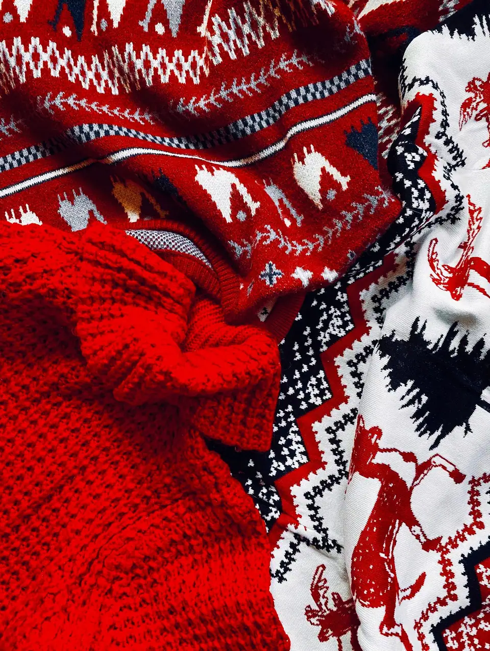 Close-up of red and white knitted Christmas sweaters with Fair Isle and reindeer patterns