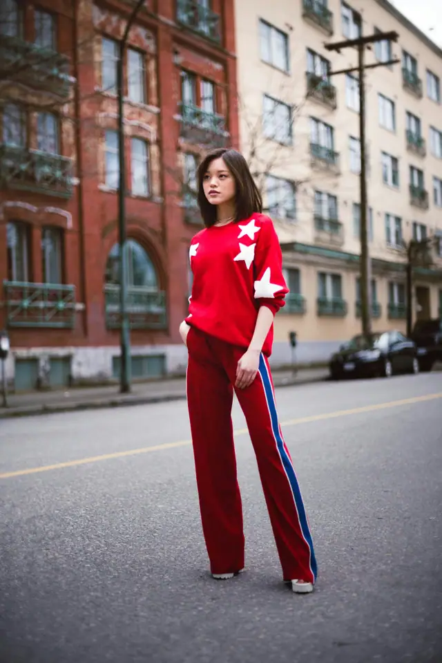 A woman in a red sweater with white stars and red track pants